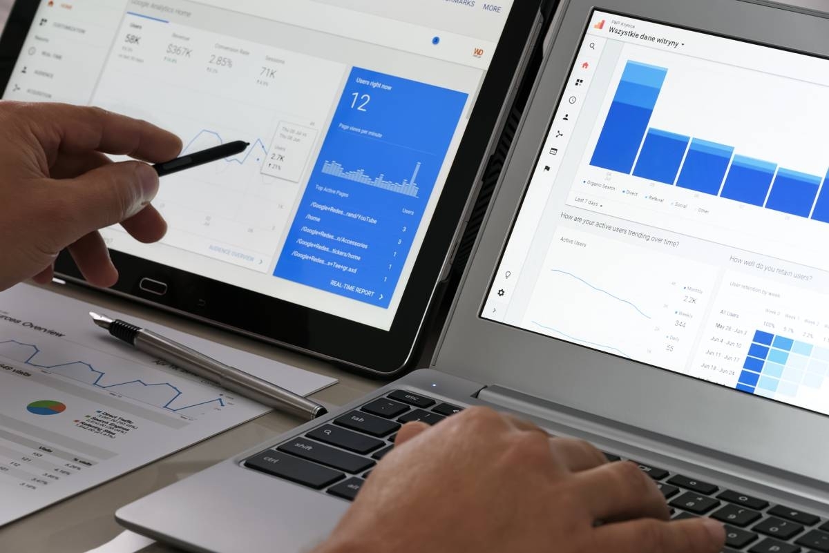 man researching and studying analytics on google analytics platform. His pen points at data on the screen of his laptop