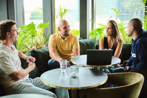 A team of people sitting together, listening to someone who is speaking.